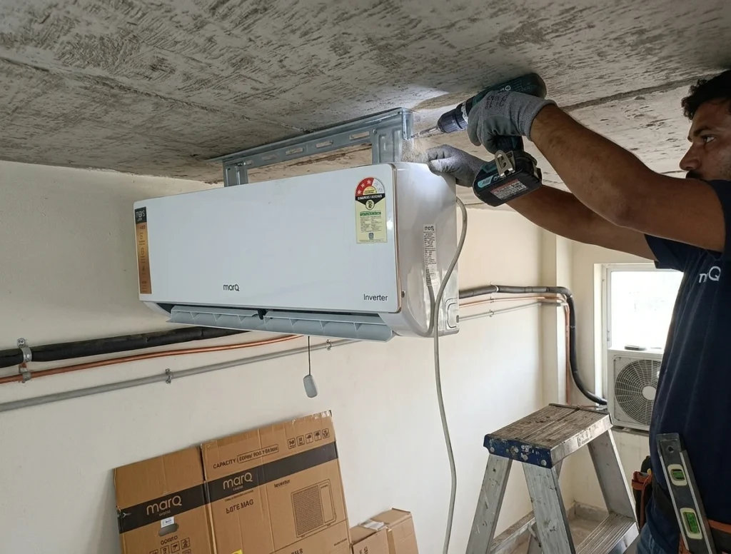A professional technician installing and checking the cooling of MarQ 1.5 Ton AC in a large living room.