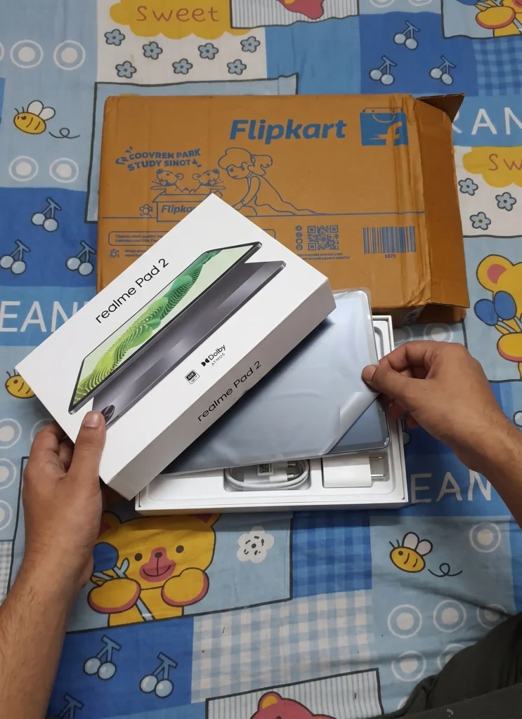 Real-life hands-on unboxing of Realme Pad 2 tablet from Flipkart delivery box showing the screen and charger